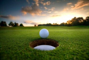 Golf ball at the edge of the cup at sunset